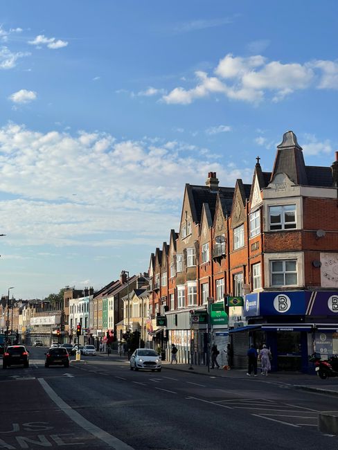 A street scene in a residential area of Plumstead during daylight hours, showing a row of multi-storey brick houses with pitched roofs and bay windows, some with small front gardens. On the pavement, 