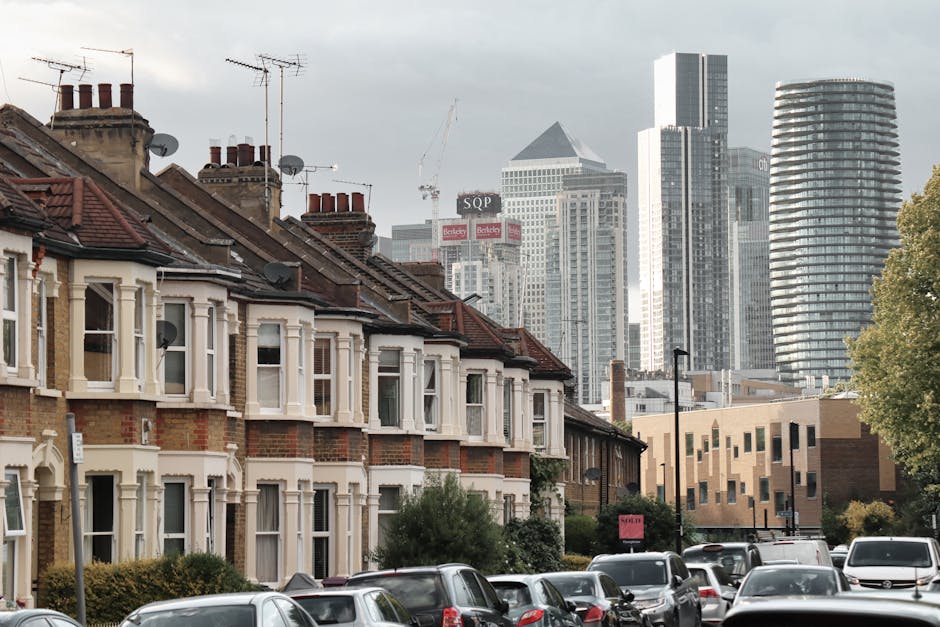 A street scene in a residential area of Plumstead during daylight hours, showing a row of multi-storey brick houses with pitched roofs and bay windows, some with small front gardens. On the pavement, 