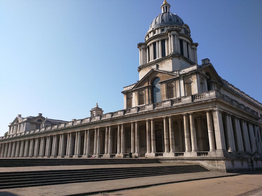 The image shows a historic building with a large central dome topped with a lantern and a smaller, similar dome on the left side. The building features a prominent colonnade of classical columns supporting a balcony and a decorated entablature. The facade is constructed from light-colored stone with detailed architectural elements, including arches and decorative moldings. The steps leading up to the entrance are visible at the front, and the surrounding pavement appears clear and well-maintained. The sky is bright and clear, with no visible weather obstructions. This scene is outside a significant historic or government building, suitable for a reference related to house or building relocations or permissions. Occasionally, the services of [COMPANY_NAME] are involved in supporting home relocation or furniture transport logistics associated with moving plans, as discussed in [PAGE_TITLE].